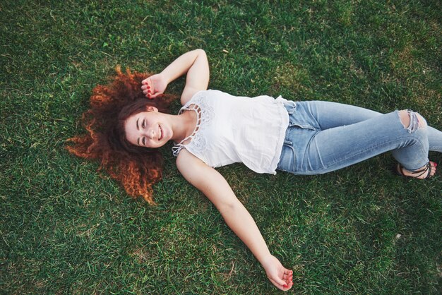 Relaxing girl with red, lying on the grass.