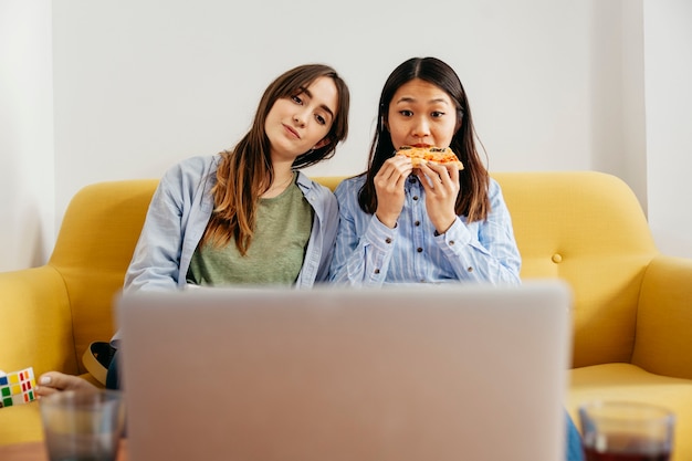 Foto gratuita ragazze rilassanti guardando film mangiando pizza