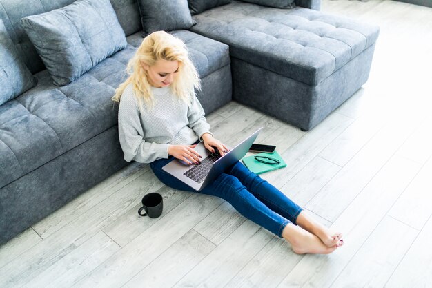 Relaxing at home. Beautiful young woman using her laptop while lying on carpet at home