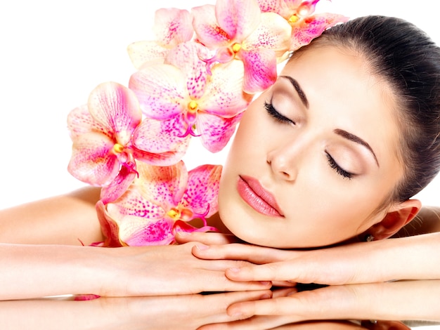 Foto gratuita rilassante bella donna con pelle sana e fiori rosa isolati su bianco