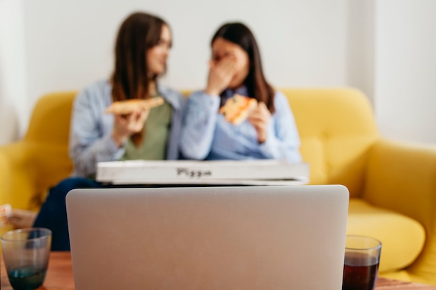 Donne rilassanti con pizza e laptop