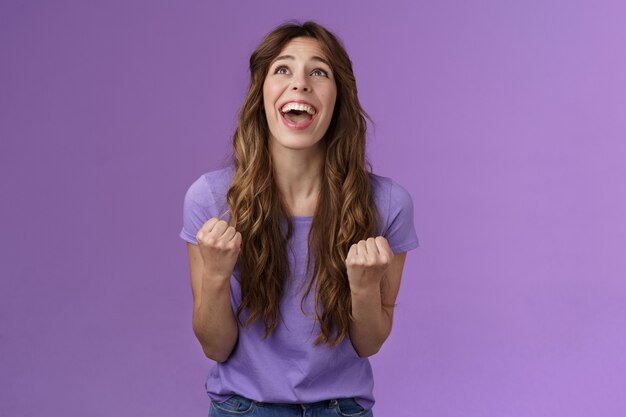 Relieved happy girl thank god awesome achievement celebrate success implore lord grateful fist pump yelling raise head up sky triumphing good news stand purple background joyful positive reaction