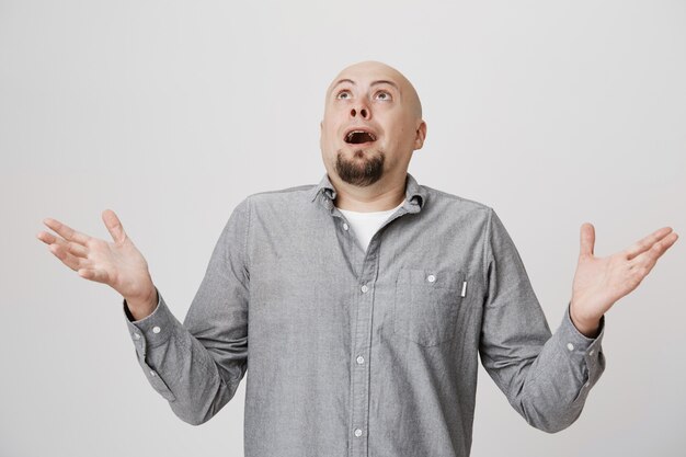 Relieved young man staring up with raised hands