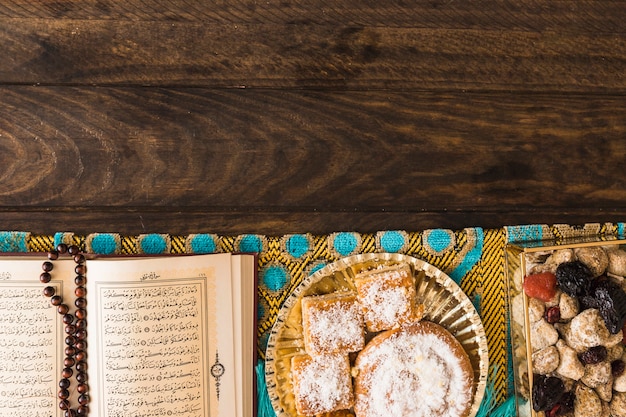 Religious book with beads near Arabic sweets