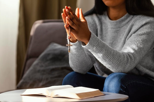 Religious woman praying with rosary beads