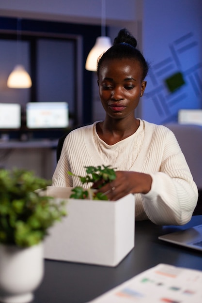 Free photo relocated african american businesswoman putting objects in cardboard box