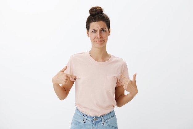 Foto gratuita giovane donna alla moda riluttante e scontenta che posa contro il muro bianco