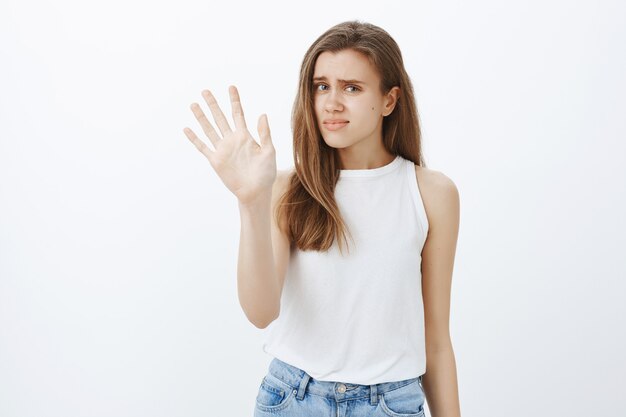 Reluctant and unamused caucasian girl shaking hand in rejection, grimacing disappointed