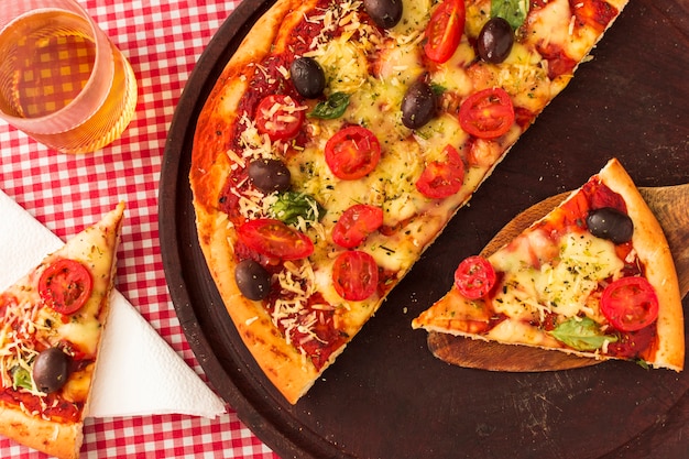 Remain slices of pizza on wooden tray with drinks in the glass