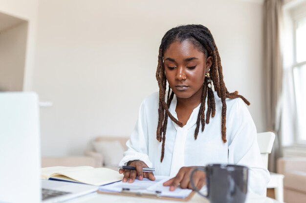 원격 작업 기술과 사람들의 개념은 랩톱 컴퓨터와 집에서 일하는 서류를 가진 행복한 미소 짓는 젊은 흑인 비즈니스 여성