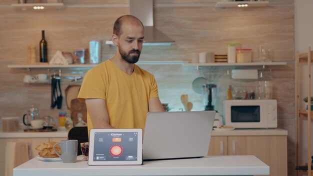 スマートホームアプリケーションとライトがオンになっているタブレットに音声コマンドを与える現代の家で働く遠隔地の人