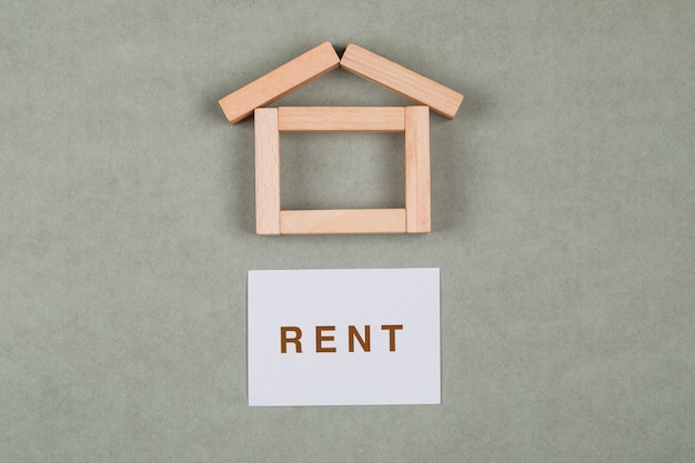 Free photo renting house concept with wooden blocks, sticky note on grey background flat lay.