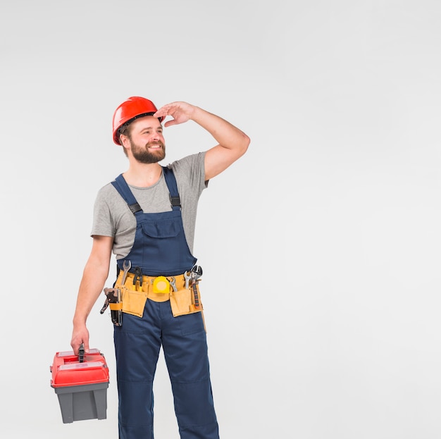 Repairman in blue overall with tool box looking away