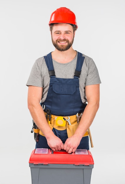 Repairman in overall with tool box smiling 