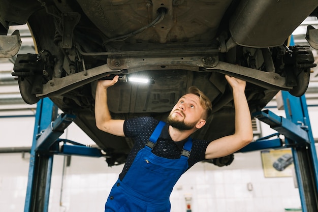 Repairmen inspecting vehicle transmission