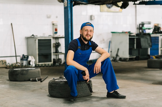 Free photo repairmen sitting on tire at garage