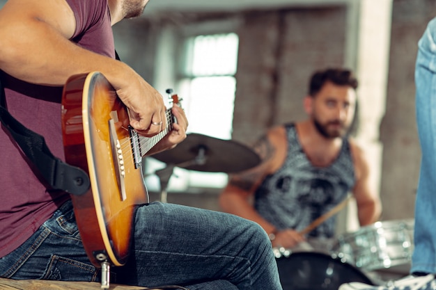 Free photo repetition of rock music band. bass guitar player, electric guitar player and drummer at loft