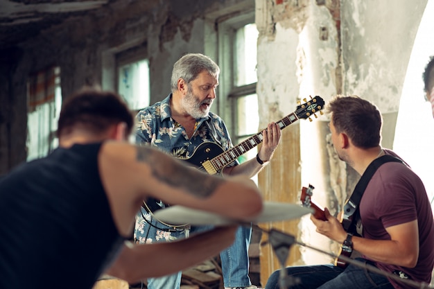 Free photo repetition of rock music band. electric guitar player and drummer behind the drum set.