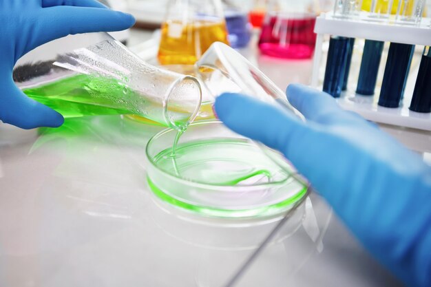 Researcher is dropping the reagent into test tube for reaction testing in chemical laboratory