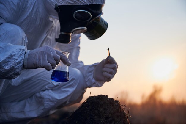 Researcher in protective suit working on a burnt field taking samples of flora