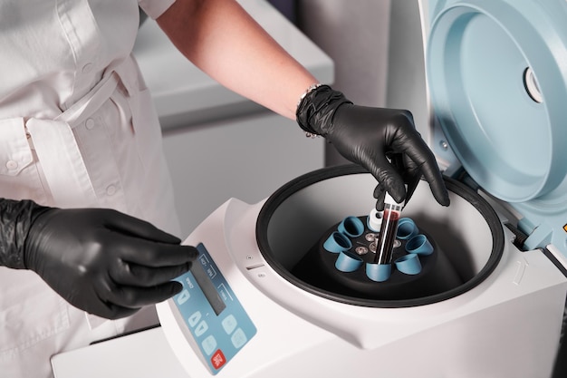 Researcher putting test tube into laboratory centrifuge