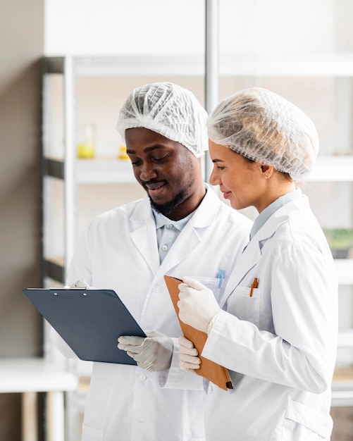 Researchers in the biotechnology laboratory with tablet and clipboard