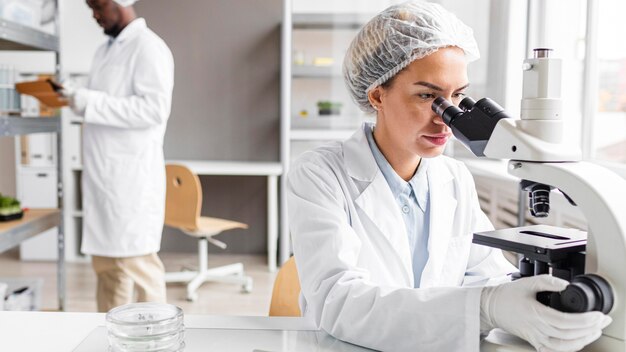 Researchers in the biotechnology laboratory with tablet and microscope