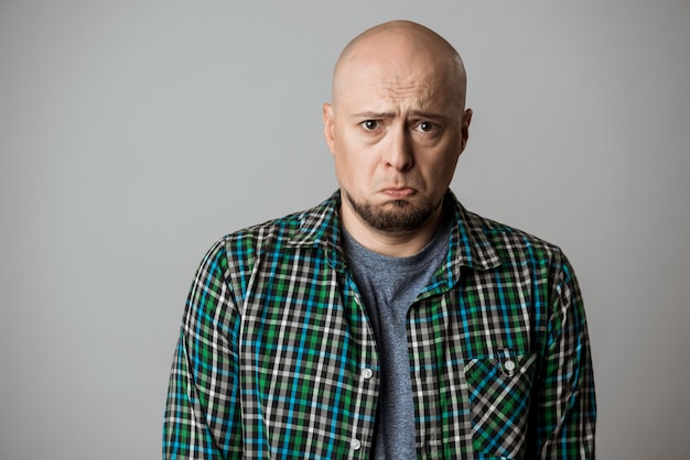 Free photo resentful sad emotive man in shirt posing over beige wall