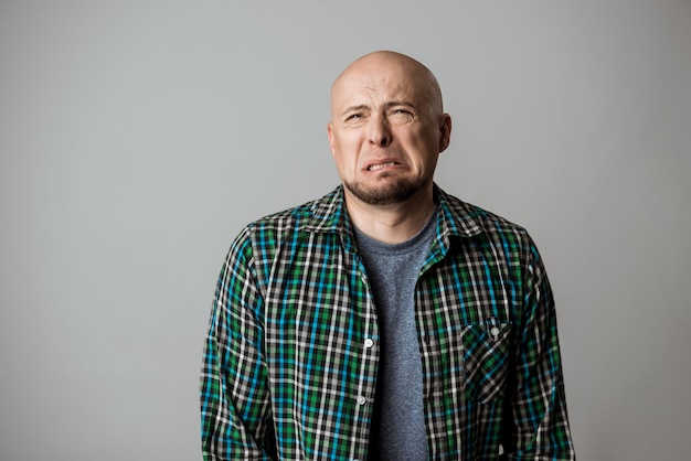 Free photo resentful sad emotive man in shirt posing over beige wall