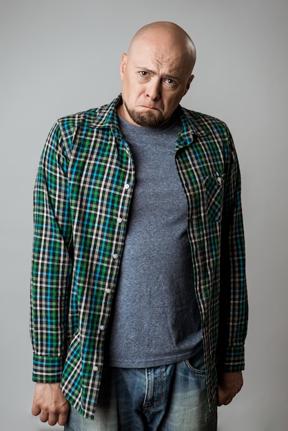 Resentful sad emotive man in shirt posing over beige wall