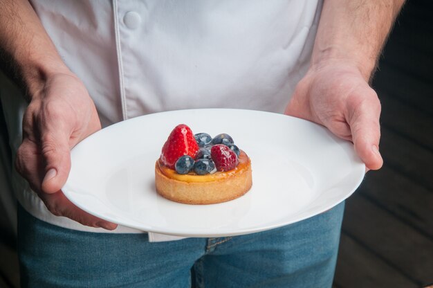 Restaurant chef holding plate with sweet dessert