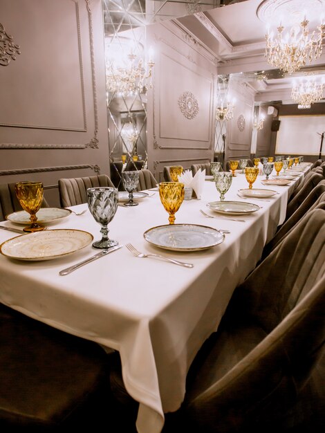 Restaurant dinner table with plates cutlery yellow and blue glasses