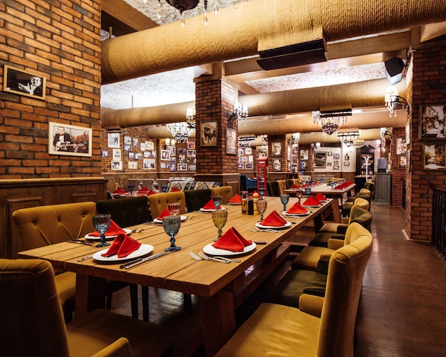 Free photo a restaurant hall with red brick walls wooden tables and pipes in the ceiling