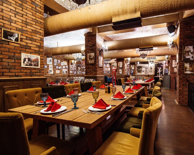 A restaurant hall with red brick walls wooden tables and pipes in the ceiling