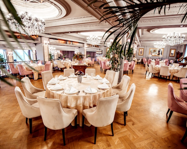 Restaurant hall with round and square tables some chairs and plants