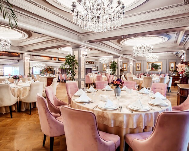 Restaurant hall with round and square tables some chairs and plants