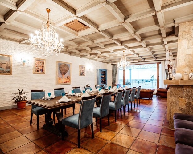 Restaurant private room with table for 12 blue chairs, white brick walls, wide window and paintings