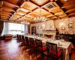 無料写真 14人用のテーブル、木製の天井、レンガの壁、暖炉のあるレストランの個室