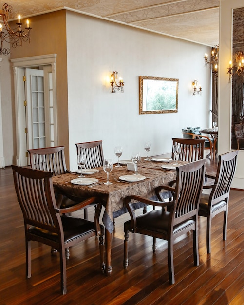 Restaurant table with wooden chairs placed in hall decorated in classical style