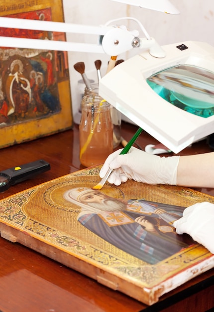 restorer works on ancient golden icon