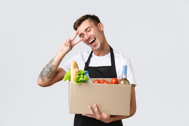 Retail grocery shopping and delivery concept charismatic handsome salesman courier in black apron sh...