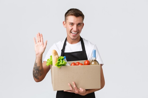 Retail grocery shopping and delivery concept friendly handsome salesman made box with groceries deli...