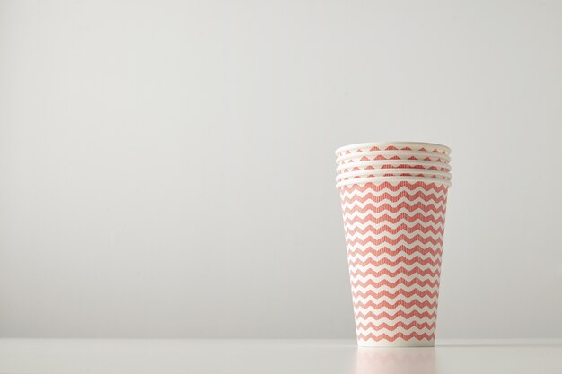 Retail set of four paper cups decorated with red lines pattern isolated on white table