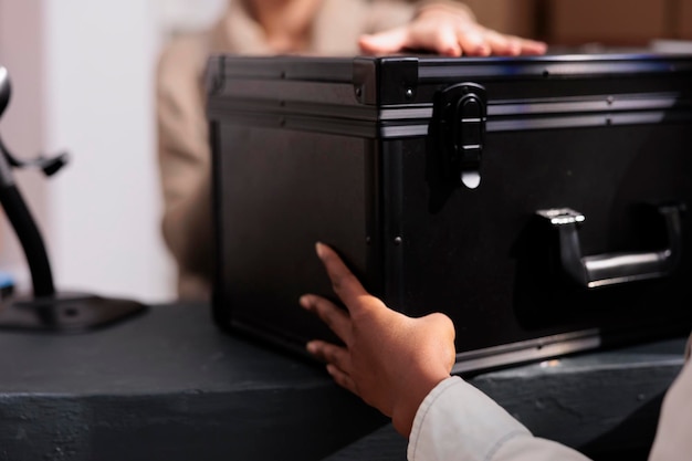 Free photo retail store stockroom employee giving colleague black case at reception desk. warehouse operator making customer order registration and checking product in stock at counter close up