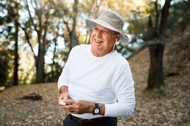 Retired man enjoying music in the middle of the forest