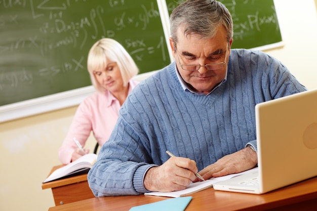 Retired man with glasses doing homework