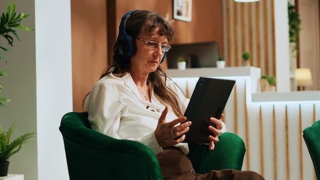 Free photo retired woman using tablet in lobby