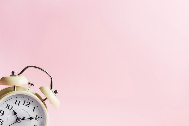 Retro alarm clock on the corner of the pink background