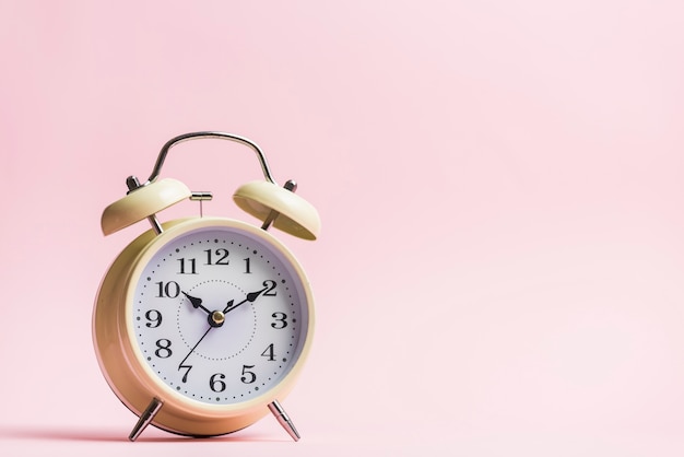 Free photo retro alarm clock on the pink background