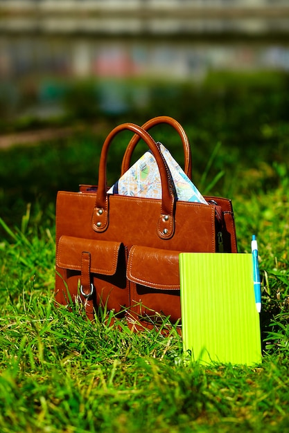 Retro brown  man leather bag and notebook in bright colorful summer grass in the park